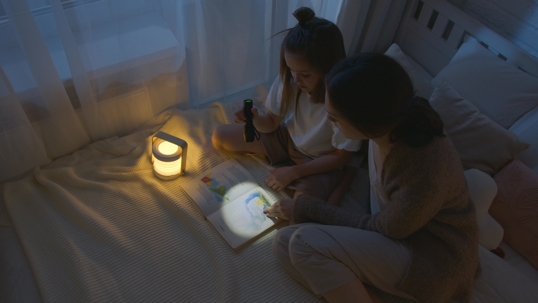 mother and child reading in dark on bed